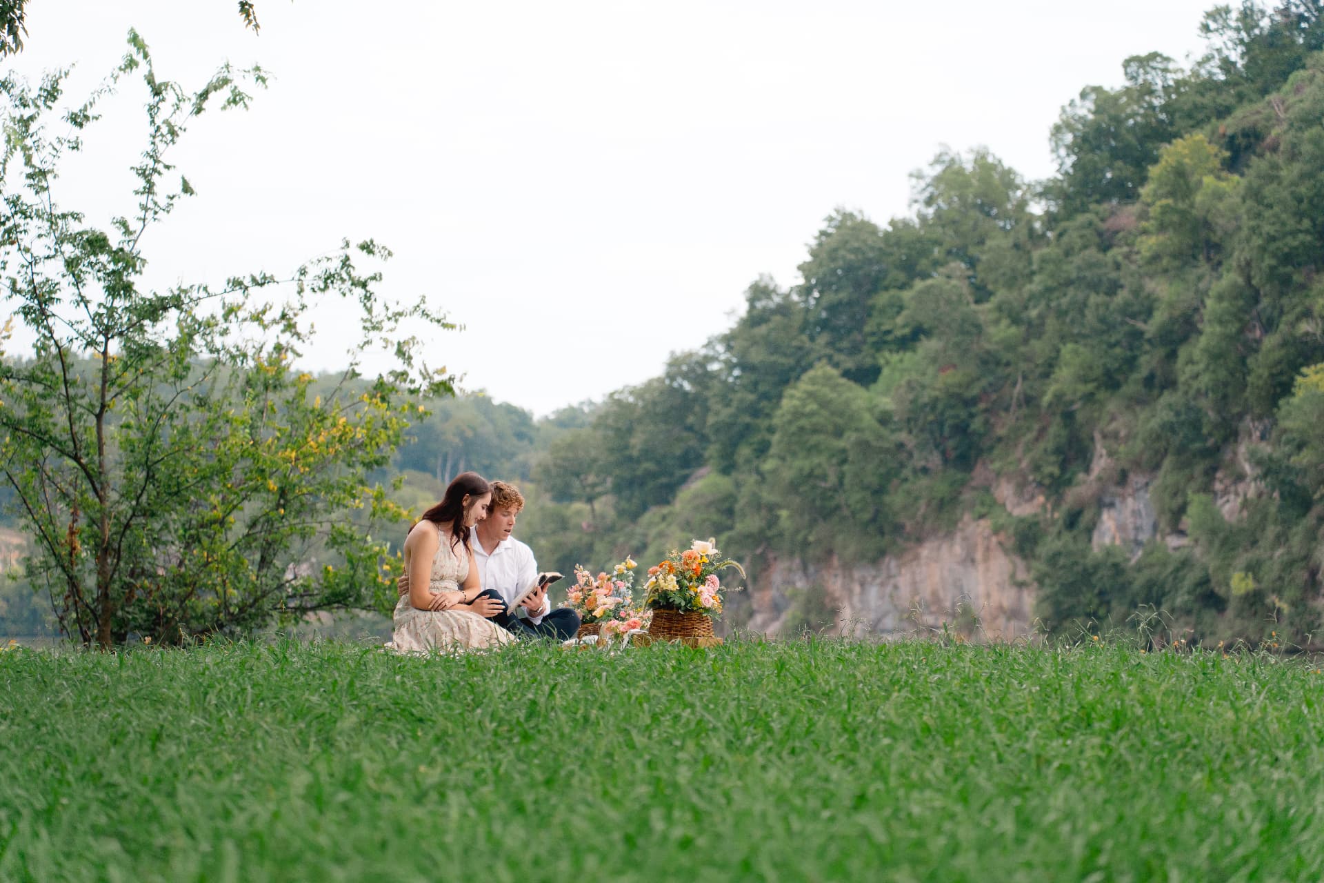 The couple reading together on a blanket by the river